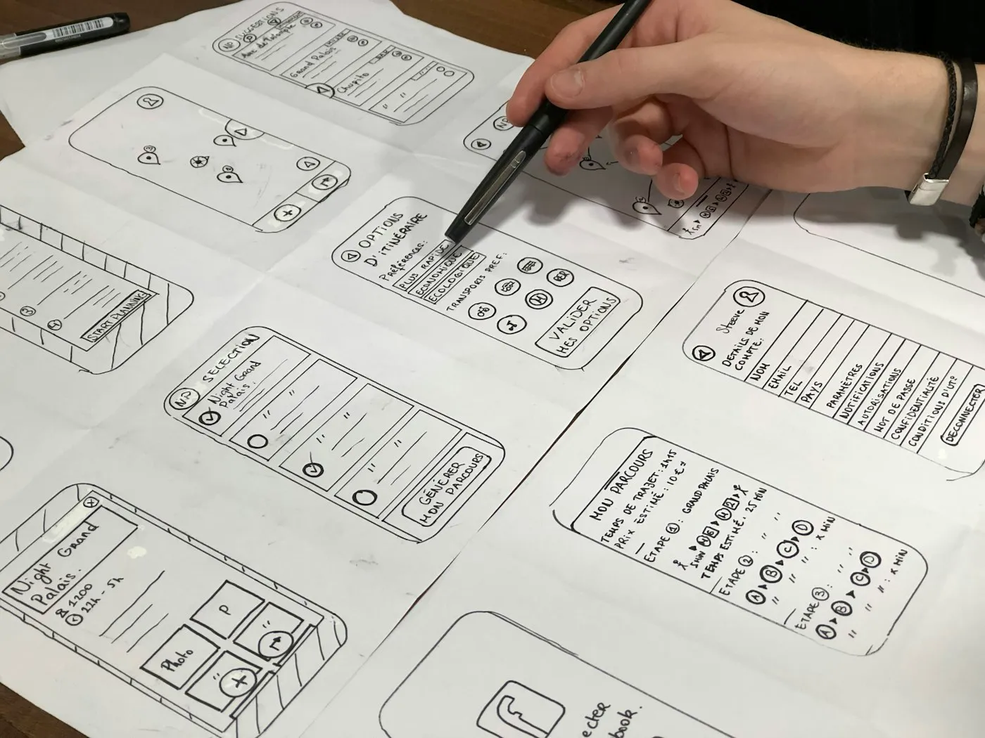 A hand sketching mobile interface wireframes on paper